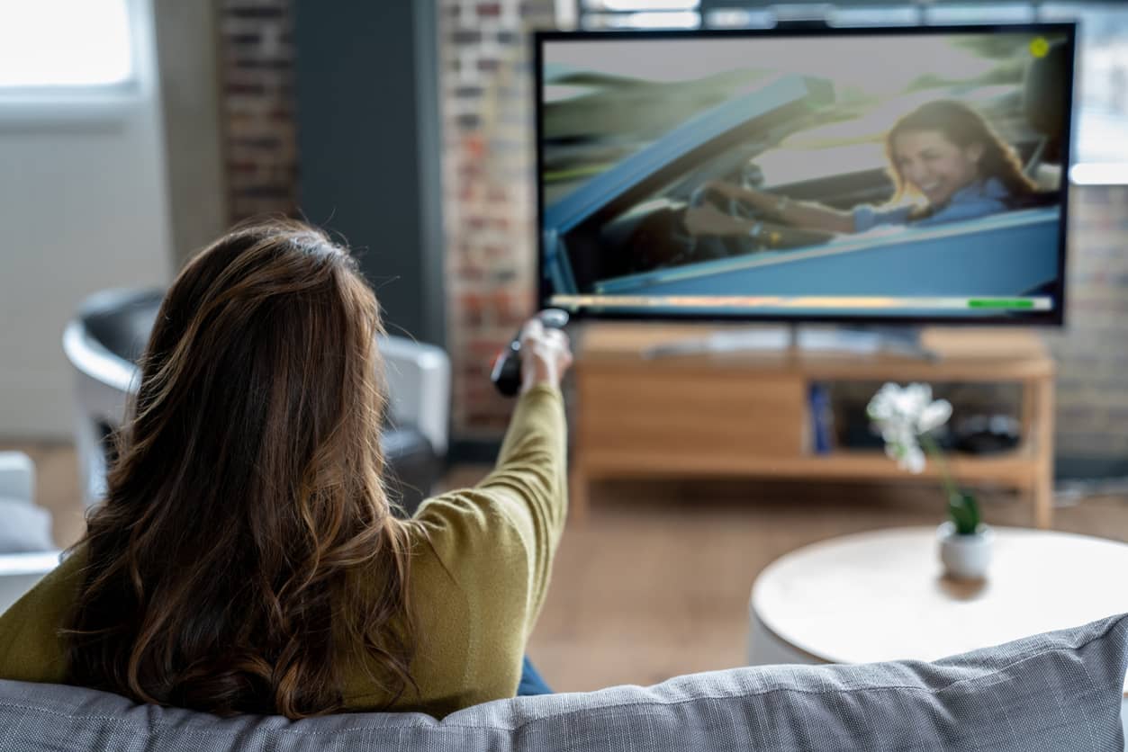 rear view of woman changing the channel on her tv