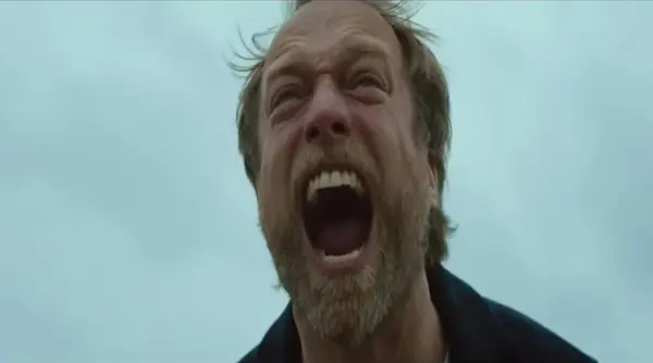 Image of a man screaming in the middle of nowhere, a scene from Speak No Evil, streaming on Shudder.