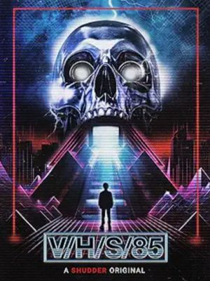 The V/H/S/85 poster art shows a person standing before a pink and purple ramp leading to a giant skull with open, glowing mouth and eyes. The film is covered in How to Watch the V/H/S Movies in Order.