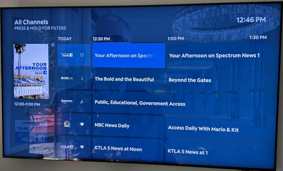 A home TV showing a TV Guide view using Apple TV's Spectrum cable TV app.